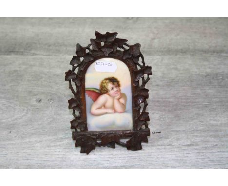 19th century Black Forest Carved Wooden Frame with Hand Painted Ceramic Panel depicting a Cherub