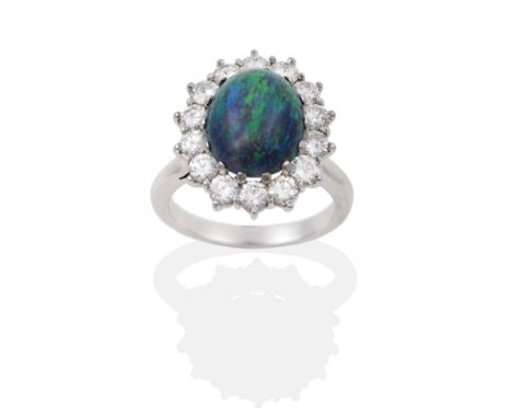 A Black Opal and Diamond Cluster Ring, the oval cabochon opal within a border of fourteen round brilliant cut diamonds, in wh