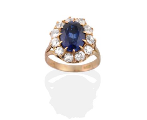 A Synthetic Sapphire and Diamond Cluster Ring, an oval cut synthetic sapphire in a claw setting, within a border of old cut d