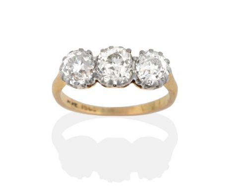 A Diamond Three Stone Ring, three old cut diamonds in white claw settings, to a yellow tapered shoulder plain polished shank,