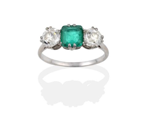 An Emerald and Diamond Three Stone Ring, the octagonal step cut emerald flanked by two old cut diamonds in white double claw 