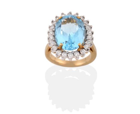 A 9 Carat Gold Blue Topaz and Diamond Cluster Ring, an oval cut topaz in a yellow four claw setting, within a border of round