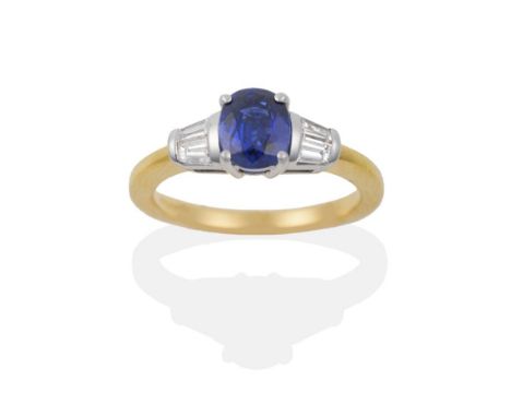 An 18 Carat Gold Sapphire and Diamond Ring, an oval mixed cut sapphire flanked by two tapered baguette cut diamonds on each s