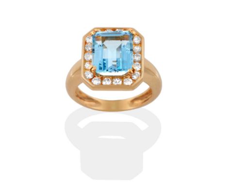 An Aquamarine and Diamond Cluster Ring, an emerald-cut aquamarine in a yellow four claw setting, within a border of round bri