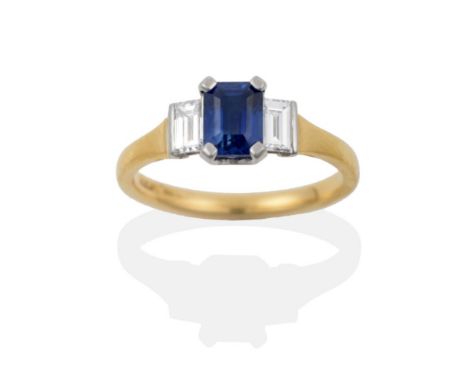 An 18 Carat Gold Sapphire and Diamond Three Stone Ring, the octagonal step cut sapphire flanked by a baguette cut diamond on 