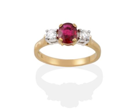 An 18 Carat Gold Ruby and Diamond Three Stone Ring, the oval mixed cut ruby in a yellow claw setting between two round brilli