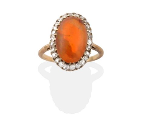 A Fire Opal and Diamond Cluster Ring, an oval cabochon fire opal within a border of old cut diamonds in yellow claw settings,