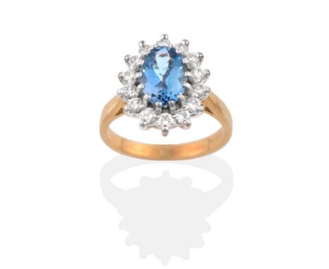 An 18 Carat Gold Aquamarine and Diamond Cluster Ring, an oval cut aquamarine within a border of round brilliant cut diamonds 