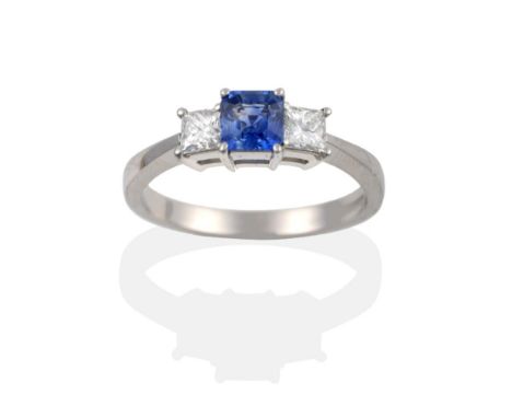 A Platinum Sapphire and Diamond Three Stone Ring, the square octagonal step cut sapphire between two princess cut diamonds, i