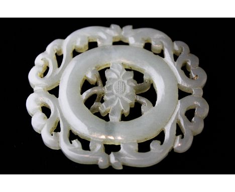 A Chinese carved oval jade pendant with flower centre and scroll border, 5cm by 4cm