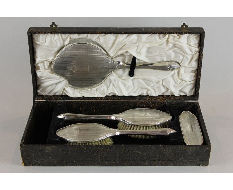 A five-piece silver back dressing set in case Birmingham 1932, with engine turned decoration, comprising mirror, two hair bru