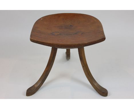A Liberty & Co Limited mahogany stool with shaped seat and three splayed legs (NC)
