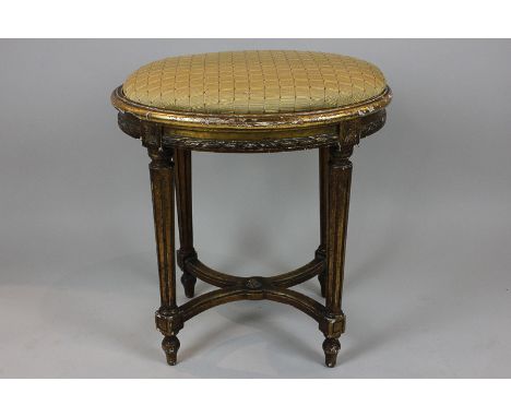 A gilt oval top dressing stool of Louis XVI style on reeded turned legs