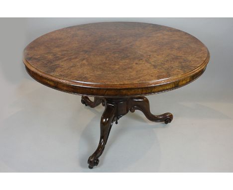 A Victorian circular dining table with figured and burr walnut tilting top, on carved pedestal and scroll tripod base, 122cm