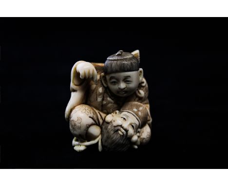 A late 19th, early 20th century carved ivory and decorated Japanese netsuke of a seated man pointing to a bearded head in his