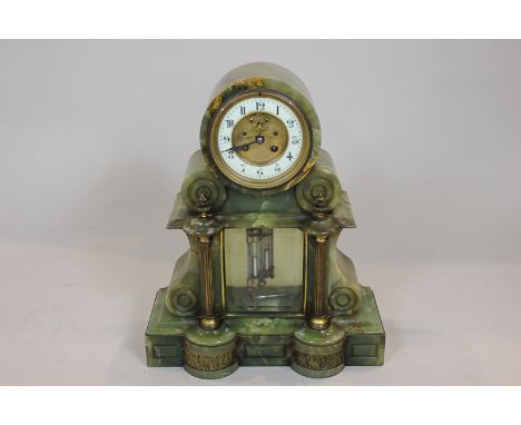A Victorian green onyx mantel clock with circular dial and visible escapement and Roman numerals, the case with brass column 