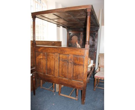 A 17th century style double size oak four poster bed with double arch and carved panelled foot board and turned columns suppo
