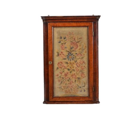 
	
		A walnut and feather-banded corner cabinet, mid-18th century and later, the door inset with a floral embroidered panel a