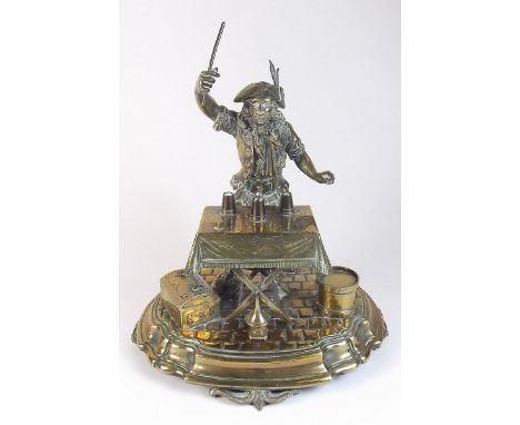 A 19th century brass inkstand and table bell in the form of a street magician with hinged hat, dome top stamp box, seal and d