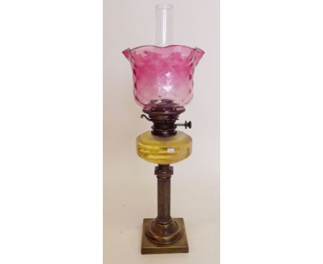 A Victorian brass column form oil lamp with yellow glass reservoir, cranberry shade and Messengers No 2 burner