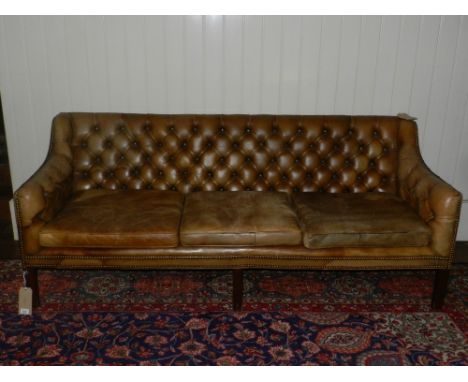 A George III style green leather button upholstered sofa, with three loose cushions, on moulded square legs, 188cm.