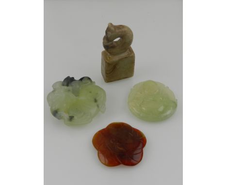 A carved jade pendant depicting Buddha, together with a further jade carving of a dragon, a red jade carving of a fish, and a