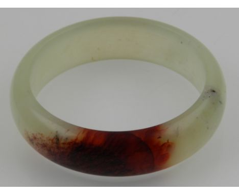 A Chinese green and russet jade bangle. D: 7cm