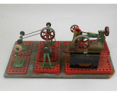 A Mamod static steam engine, the boiler driving a variety of workshop tools and equipment, on a wooden base, W. 40cm.