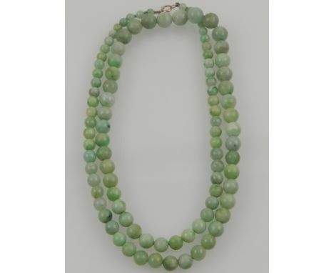 A string of graduated green jade beads, fastened with a yellow metal clasp. 