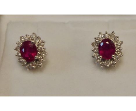 A pair of ruby and diamond cluster ear studs, each oval ruby surrounded by sixteen brilliant cut diamonds 