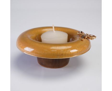 A luxurious Jay Strongwater candle holder featuring a ribbed, golden amber enamel surface and elegant circular form with a fl