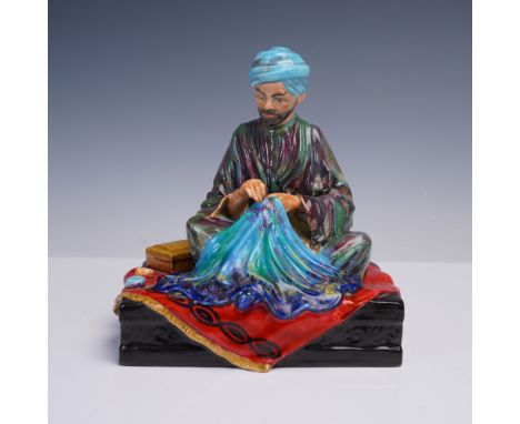 This studio pottery figurine titled Embroiderer of Kashmir is the work of studio potter R. Johnson. It depicts a seated figur