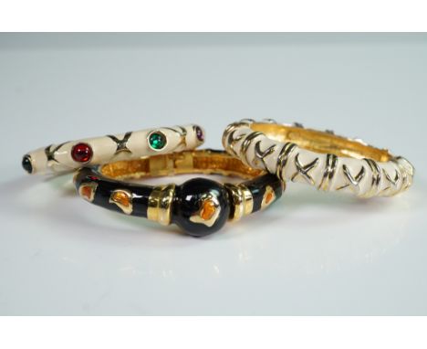 Set of three hinged bangle bracelets featuring colorful enamel inlay and gold-tone accents. One bracelet is designed with mul