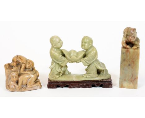 Three oriental soapstone and jade carvings, one in the form of two young boys carrying a rock, on a rectangular base, 12cm W,