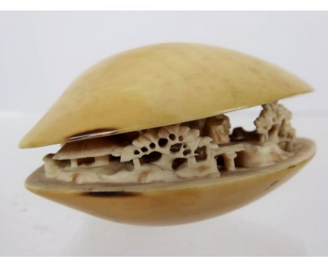 A 19th Century Japanese Ivory Netsuke, in the form of a clam, carved with figures in a garden, approx 6 x 8 cms, character ma