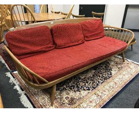 An Ercol elm day bed with red upholstered cushions