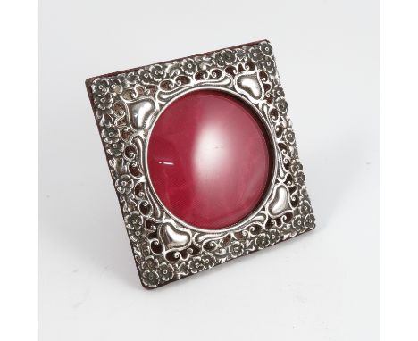 A silver mounted photograph frame, of square form with circular aperture, the pierced silver mount decorated with flowers and