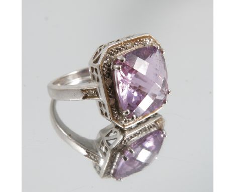 A 9ct white gold amethyst and diamond dress ring, the cushion shaped stone enclosed by single cuts, finger size P 1/2, weight