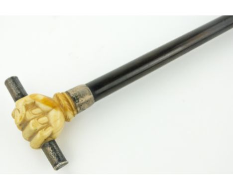 An ebony walking cane
with knop of a marine ivory carved fist holding a silver baton.