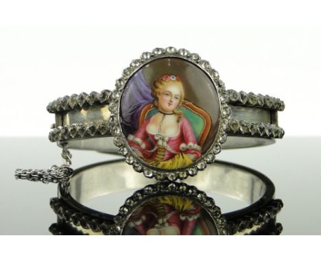A 19th century unmarked silver hinged bangle
with inset painted enamel portrait of a woman in paste surround.