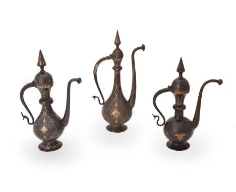 Three Qajar damascened and engraved steel ewers, Persia, circa 1800-1900, with slender necks, s-shaped handles and curved spo