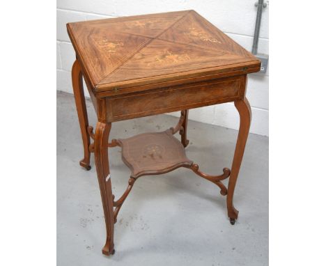 A walnut and inlaid fold out card/games table with uniting under tier on casters, width when extended 80cm.