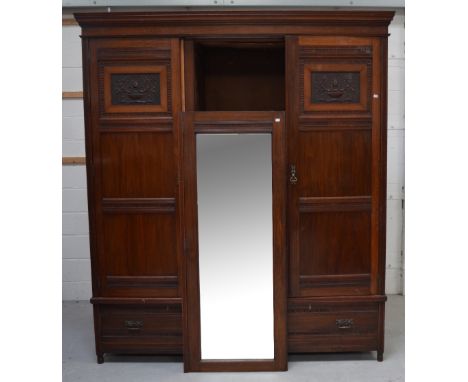 A Victorian mahogany three door wardrobe, the central mirror door flanked by panelled and carved doors either side, three int