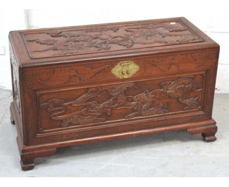 An Oriental carved camphor wood chest on bracket feet with brass fittings, length 93cm.
