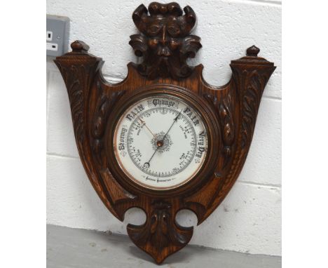 A heavily carved oak aneroid wall barometer, height 56cm.