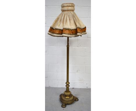 An early 20th century brass standard lamp with reeded column on shell design stand and three highly decorated round feet, hei