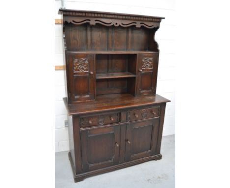 An oak priory style dresser, boarded plate rack and doors with carved decoration of animals and birds above two short drawers