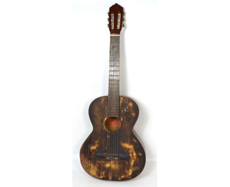 A six string acoustic guitar bearing a poem, 'In times when nothing stood, but worsened or grew strange, there was one consta