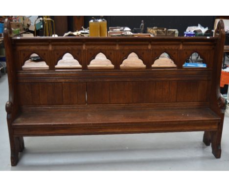 A 19th century oak church pew with carved boards to the sides, arched carvings to the back and a shelf for prayer books, 137 