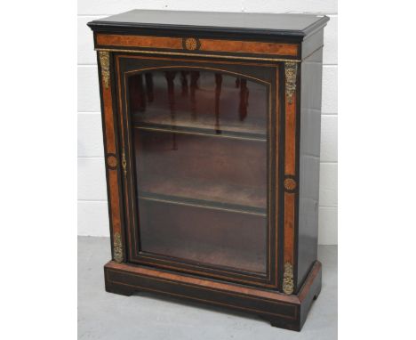 An ebonised pier cabinet, single glazed door with interior shelving flanked by walnut banding and with applied gilt metal mou